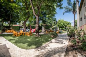a garden with a hammock and tables and trees at Nuriel Fruit & Guest House in Sheʼar Yashuv