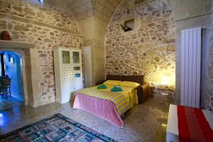 una camera con letto e parete in pietra di Dimora Storica San Giovanni a Zollino