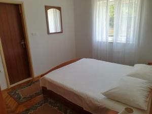 a bedroom with a white bed and a window at Apartments Jelić in Banići