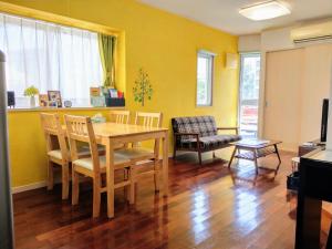a dining room with a table and chairs and yellow walls at Duplex Makishi in Makishimachi