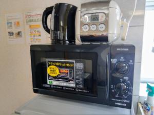 a microwave with a coffee pot on top of it at Duplex Makishi in Makishimachi