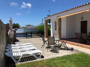un patio con sillas blancas, una mesa y una valla en Chalet Ventura en Conil en Conil de la Frontera