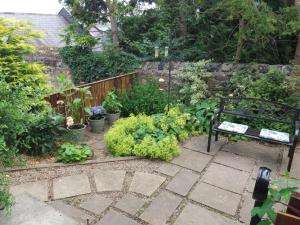 a garden with a bench and some plants at Hedgehope Cottage Alnwick in Alnwick