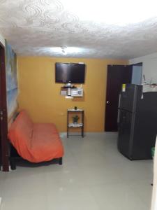 Habitación con TV, silla y nevera. en Posada J&J Forbes - 2, en San Andrés