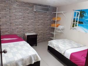 1 dormitorio con 2 camas y pared de ladrillo en Posada J&J Forbes - 2, en San Andrés