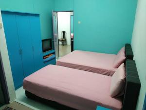 1 dormitorio con 2 camas, TV y pared azul en Formosa Hotel Apartment en Melaka