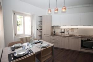 a kitchen with white cabinets and a table with chairs at Il Golfo Apartment in Lenno