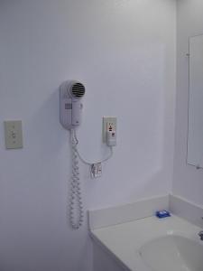 a phone hanging on a wall in a bathroom at Economy Inn in Willows