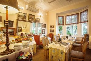 una sala da pranzo con tavoli, sedie e finestre di Goble Palms Guest Lodge & Urban Retreat a Durban