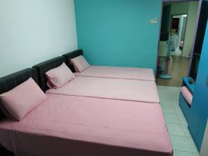 2 Betten in einem Zimmer mit rosa Bettwäsche und Kissen in der Unterkunft Formosa Hotel Apartment in Malakka