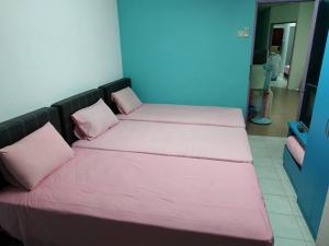 two beds in a room with pink sheets and pillows at Formosa Hotel Apartment in Melaka