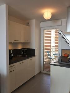 a kitchen with white cabinets and a table and chairs at Meuble de tourisme classé, climatisation, pieds dans l'eau in Palavas-les-Flots