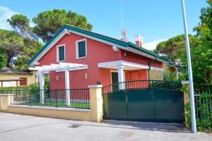 een rood huis met een hek en een hek bij Green Marine Family Villas in Lido di Jesolo