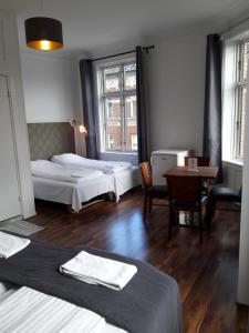 
a bedroom with a bed, chair, table and lamp at Hotel Løven in Copenhagen
