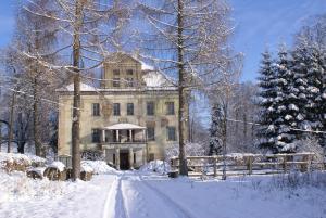 an old house in the snow with a snow covered driveway at Pałac Rząsiny in Gryfów Śląski