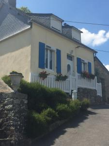 a white house with blue shutters and flowers on it at Gite avec vue dominante in Châteaulin