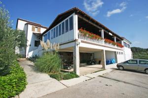 a white house with a balcony with flowers on it at Jurman Apartment in Barbariga