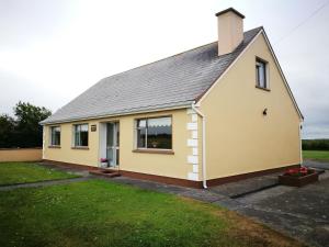 una casa gialla con tetto grigio di Danubio Guest Accommodation a Doonbeg