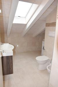 een badkamer met een toilet, een wastafel en een dakraam bij Green Marine Family Villas in Lido di Jesolo