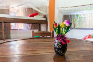 um vaso preto com flores sobre uma mesa de madeira em Casas do San Caraíva - Turma em Caraíva