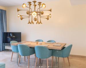 a dining room table with blue chairs and a chandelier at Golf Beach and Relax Townhouse in La Alcaidesa