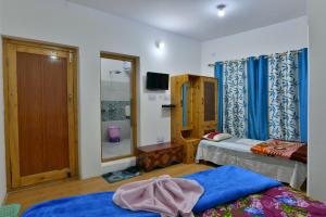 a room with two beds and a window and a tv at Lhachik Guest House in Leh