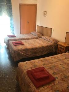 three beds in a hotel room with a red towel on them at Hostal L'Escaleta in Oropesa del Mar