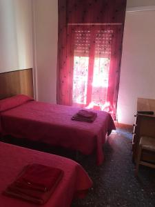 Un dormitorio con 2 camas y una ventana con sábanas rojas. en Hostal L'Escaleta, en Oropesa del Mar