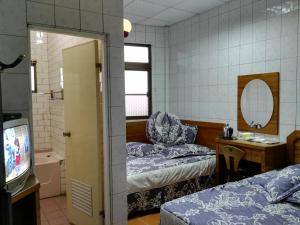 a room with two beds and a mirror and a tv at Qun Feng Hotel in Fenqihu