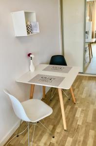 una mesa blanca con 2 sillas y un jarrón de flores en Apartament MetroMarymont en Varsovia