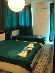 two beds in a room with blue curtains at Деси Къща за гости 1 in Chernomorets