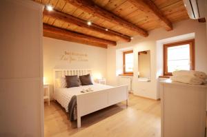 1 dormitorio con cama blanca y techo de madera en Matijevi Apartments, en Sistiana