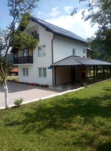 uma casa branca com um telhado preto e um quintal em Apartments Paradise em Ličko Petrovo Selo