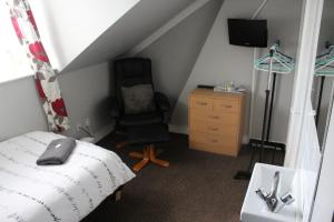a bedroom with a bed and a chair and a dresser at The Vale Hotel in Hull