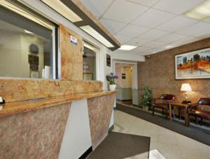 an office lobby with a reception counter and chairs at Super 8 by Wyndham Long Island City LGA Hotel in Queens