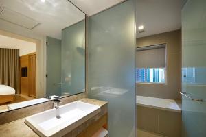 ein Bad mit einem Waschbecken, einer Dusche und einem Spiegel in der Unterkunft ANSA Hotel Kuala Lumpur in Kuala Lumpur