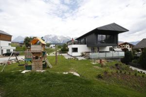 a house with a black roof and a playground at Haus Mozart in Schladming