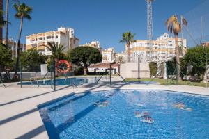 a swimming pool in a city with palm trees and buildings at Happy Nest in Benalmádena