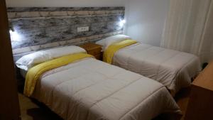 レオンにあるLARGE SUITE 90m2 LEÓN CENTROの白いシーツと黄色の毛布が備わる客室のベッド2台