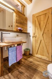 a bathroom with a sink and a wooden door at Casa de Fiemme in Tesero