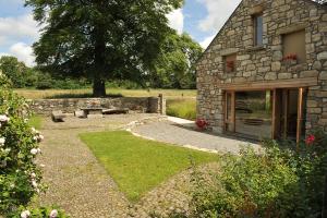 a stone building with a bench and a table at Blackstairs Shepherds Huts in Killedmond