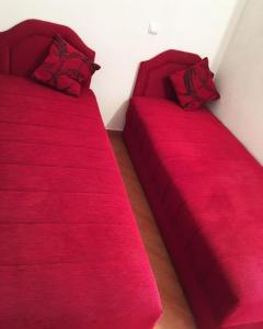 twee bedden in een kamer met rode lakens en kussens bij Sutomore apartments Anika in Sutomore