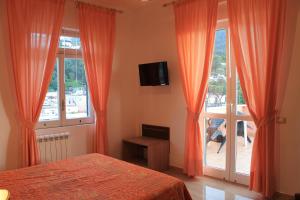 イスキアにあるHotel Terme Rosaleoのベッドルーム1室(オレンジ色のカーテン、ベッド1台、窓付)