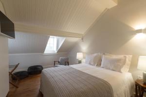 Schlafzimmer mit einem Bett mit weißer Bettwäsche und einem Fenster in der Unterkunft AQ 188 Guest House in Coimbra