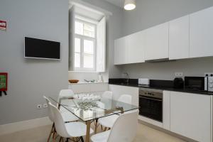 a kitchen with a glass table and white cabinets at AQ 188 Guest House in Coimbra