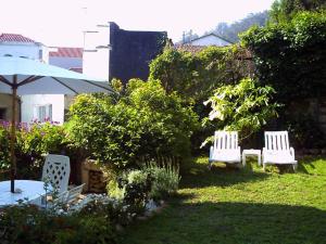 ムロスにあるA Casa da Fonteの庭に白い椅子2脚と傘