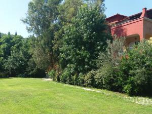 ポルト・クウフォにあるPortoAgaliの木立の赤い建物の隣の芝生の庭