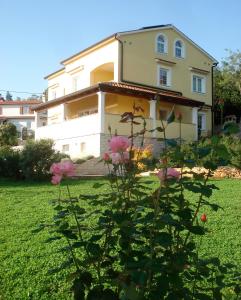 una casa con flores rosas delante de ella en Guesthouse Villa AnnaDora, en Brseč