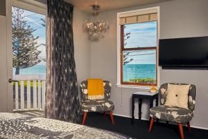 Kaikoura Boutique Hotel في كايكورا: غرفة نوم بسرير وكرسيين ونافذة