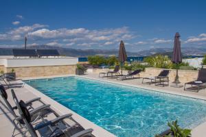 a pool with chairs and umbrellas on a house at Luxury Poolside Villa in Slatine